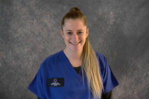 nurse wearing blue scrubs against a gray backdrop